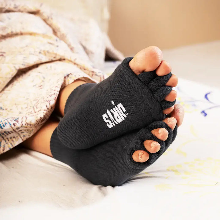 Person holding burning feet at night