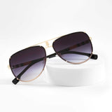 Elegant gold blue sunglasses with gradient lenses on white stand