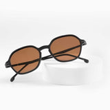 Dark brown sunglasses with amber lenses on white stand