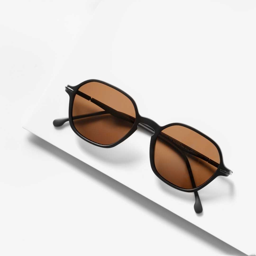 Dark brown sunglasses with amber lenses on white surface