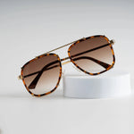 Tortoiseshell sunglasses displayed on white stand